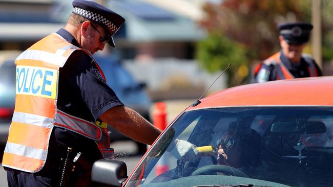 A police officer conducts a random breath test on a driver on Military Road at Taperoo. Picture: Simon Cross