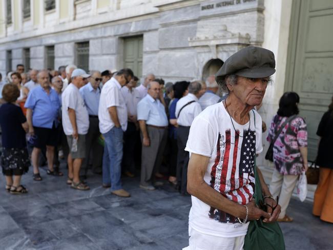 Lining up for money ... The first customers, most of them pensioners, stand in a queue to enter a branch at National Bank of Greece headquarters in Athens. Picture: AP/Thanassis Stavrakis