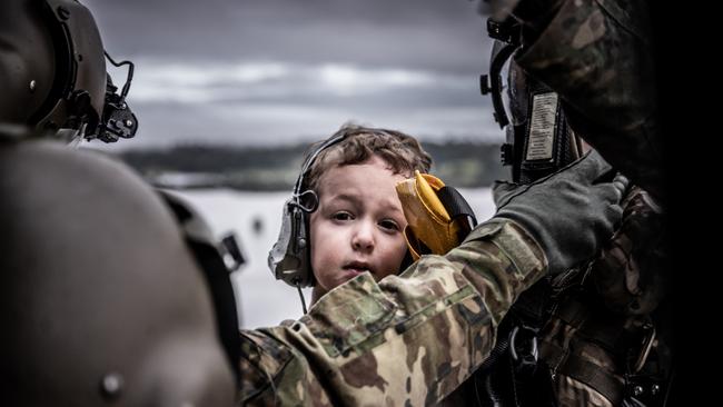 An Australian Army aircrewman from the School of Army Aviation and a young child are winched aboard an MRH-90 Taipan helicopter near Lismore during Operation Flood Assist 2022.