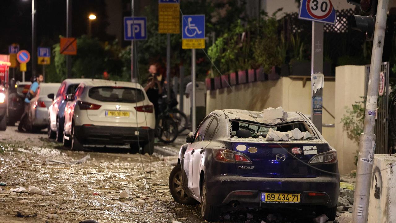 People assess the damage in a street in Tel Aviv, after it was hit by a rocket fired by Palestinian militants from the Gaza Strip. Picture: AFP