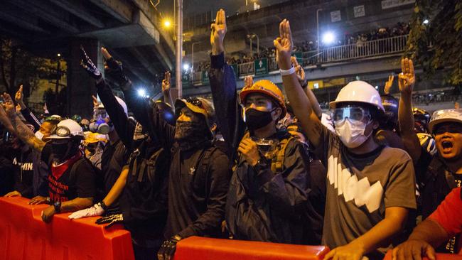 Protesters flash the symbolic Hunger Games salute as they march to Government House in Bangkok on Wednesday. Picture: Getty Images