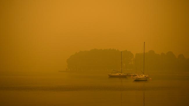 Boats are seen on Lake Burley Griffin surrounded by smoke haze. (AAP Image/Lukas Coch) NO ARCHIVING