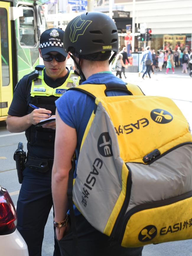 A police officer speaks with a delivery rider. Picture: Tony Gough