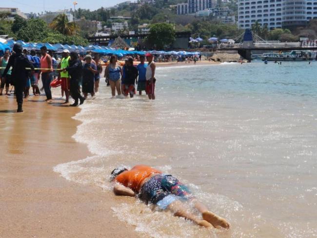 Tourists and residents in Acapulco look on after the body washed up on shore on April 15. Picture: Reuters