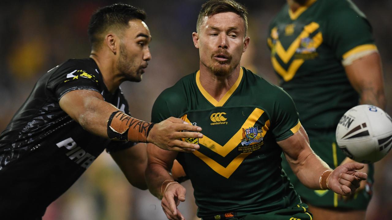 Damien Cook of the Kangaroos offloads the ball as Briton Nikora of the Kiwis moves in for a tackle