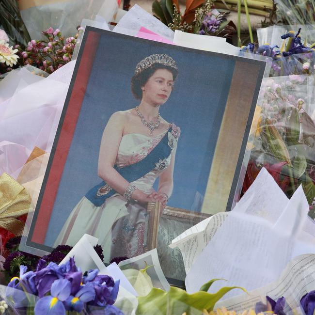 Mourners lay flowers at the base of a statue of Queen Elizabeth II at Government House in Brisbane. Picture: Sarah Marshall