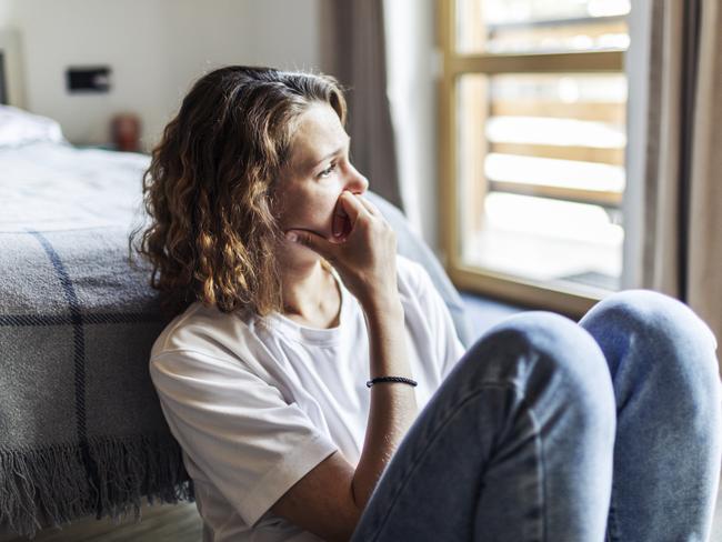 Young adult woman with depression sitting at home alone