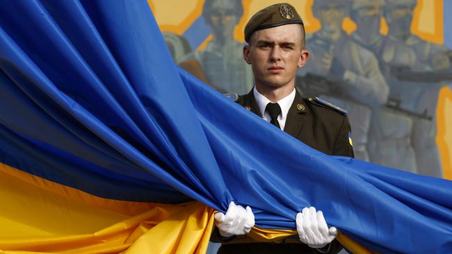 A soldier unfurls the national flag of Ukraine at Hetman Petro Sahaidachny National Ground Forces Academy on Tuesday in Lviv. Picture: Getty Images