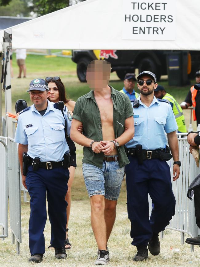 A man is led away by police from the Electric Gardens music festival in Centennial Park. Picture: Matrix