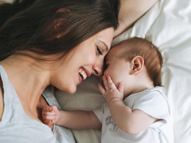 Young mother having fun with cute baby girl on bed, natural tones, love emotion