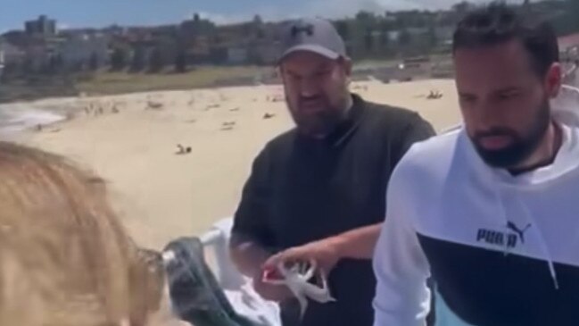 A video shared on social media appears to show two men who allegedly ripped down posters of kidnapped Israeli hostages at Bondi Beach on Thursday.