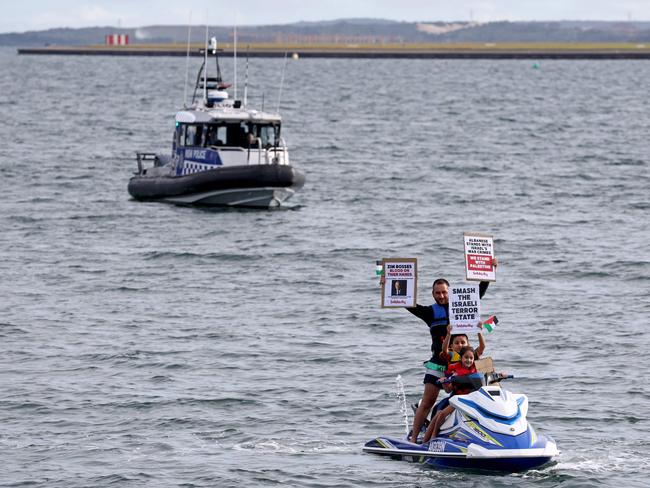 A police boat can be seen behind members of the Australian Palestinian community holding placards as they sit and stand on a jet ski. Picture: DAVID GRAY / AFP