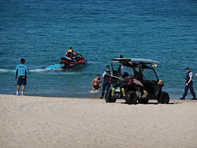 A man who ignored closed beach signs was ushered out of the water by lifeguards and police. Picture: Adam Yip