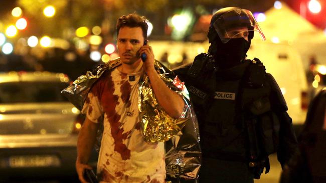 A French policeman assists a blood-covered victim near the Bataclan concert hall following attacks in Paris on November 14, 2015. Picture: Reuters