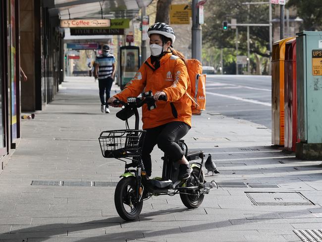 SYDNEY, AUSTRALIA - NewsWire photos AUGUST 23, 2021: A Menulog delivery person rides on the sidewalk in the Sydney CBD during COVID-19 Lockdown. Picture: NCA NewsWire / Dylan Coker