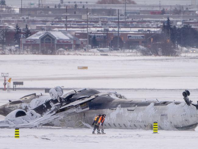 Airport workers survey the site of the Delta Air Lines plane crash. Picture: Getty