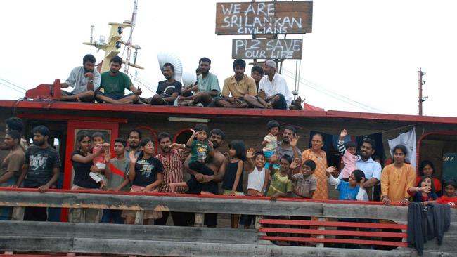Sri Lankan asylum seekers wave from a wooden boat at a port in Cilegon, Indonesian Banten province, 13/10/2009 after Australian PM Rudd confirmed that he phoned Indonesian president for help in stopping people-smuggling.