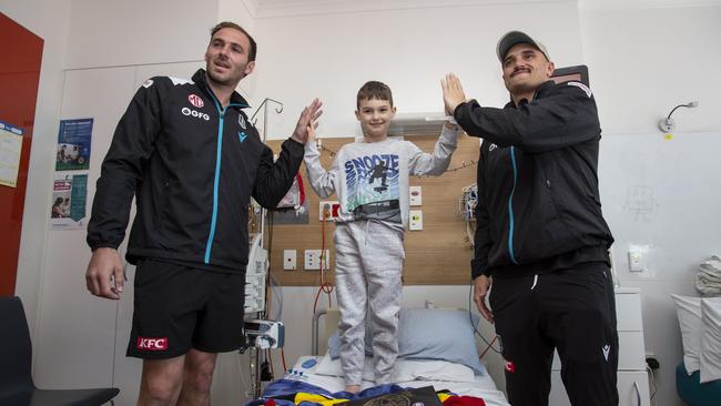 Sam Powell-Pepper and Jeremy Finlayson with Port supporter Lincoln Hassell. Picture: Brett Hartwig.