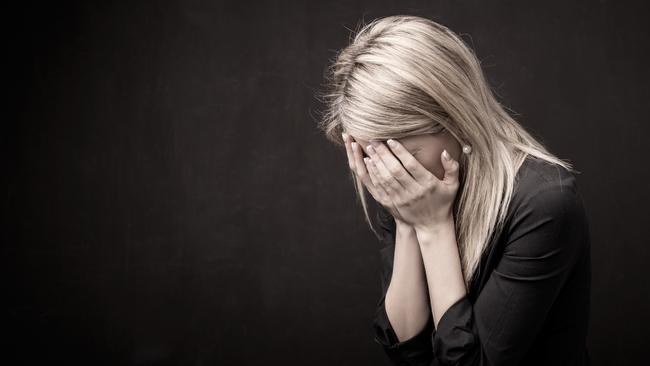 Woman holding her face in her hands. istock image