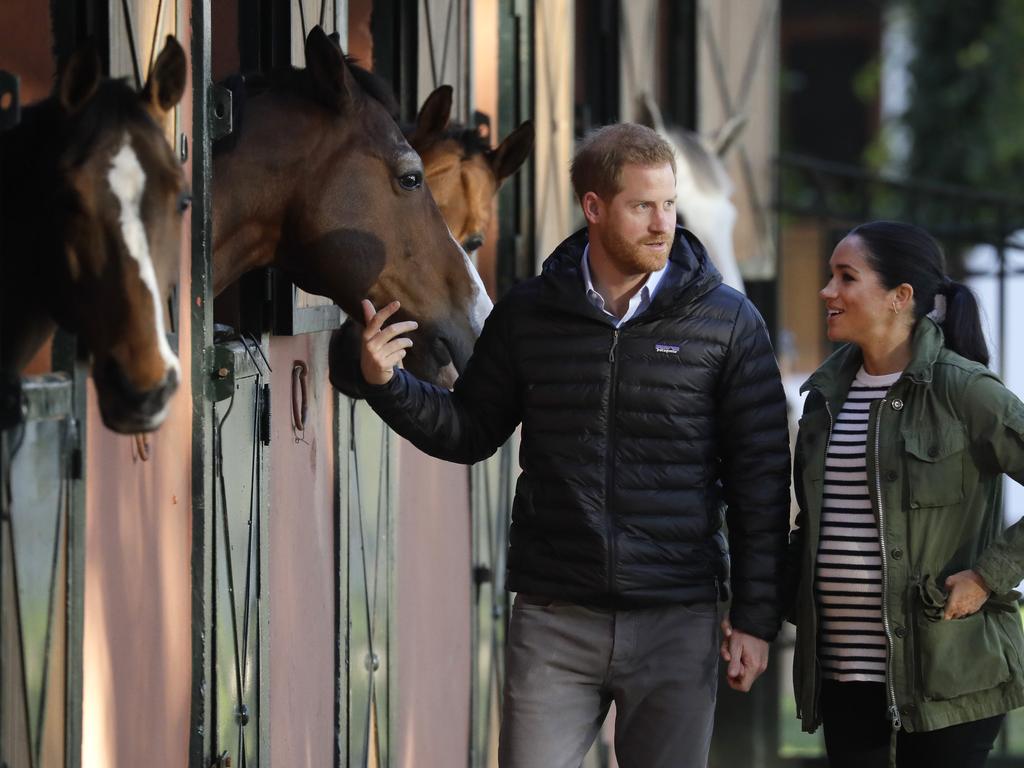  Prince Harry and Meghan stop to stroke horses in their stables during a visit to the Moroccan Royal Federation of Equestrian Sports in Rabat. Picture: AP 