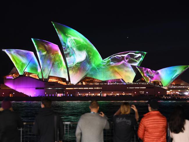 Crowds gather to watch the lights on the Opera House sails. Picture: AFP