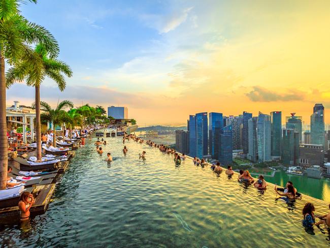 ESCAPE Singapore - May 3, 2018: Infinity Pool at sunset of Skypark that tops the Marina Bay Sands Hotel and Casino from rooftop of La Vie Club Lounge on 57th floor. Financial district skyline on background. istock