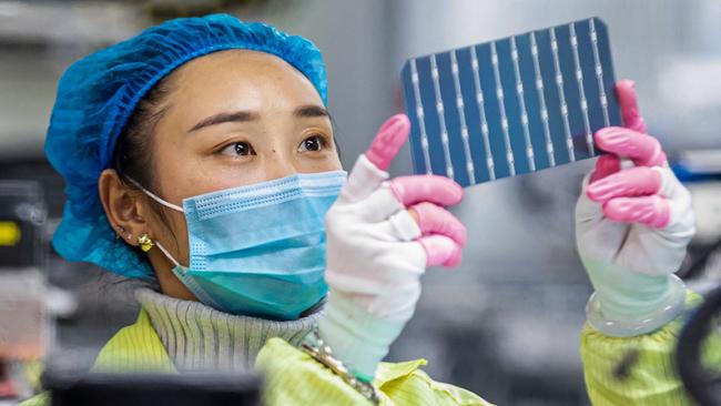 This photo taken on January 7, 2022 shows a worker checking solar photovoltaic modules used for small solar panels at a factory in Haian in China's eastern Jiangsu province. (Photo by AFP) / China OUT