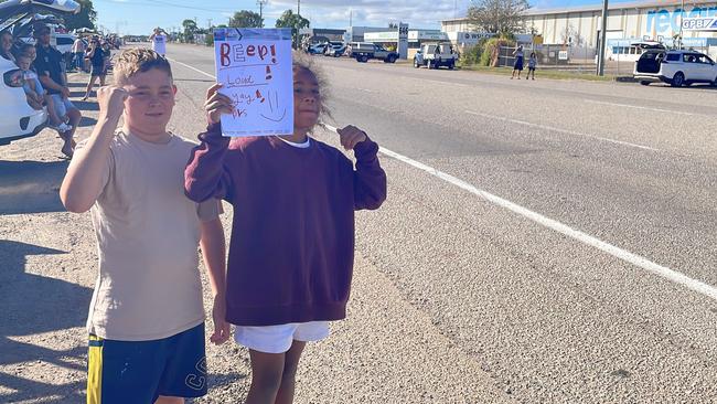 Oliver Deeble, 11, and Deja Siulai, 9, wait for the convoy at Ingham Road with a sign urging truck drivers to beep their horns.