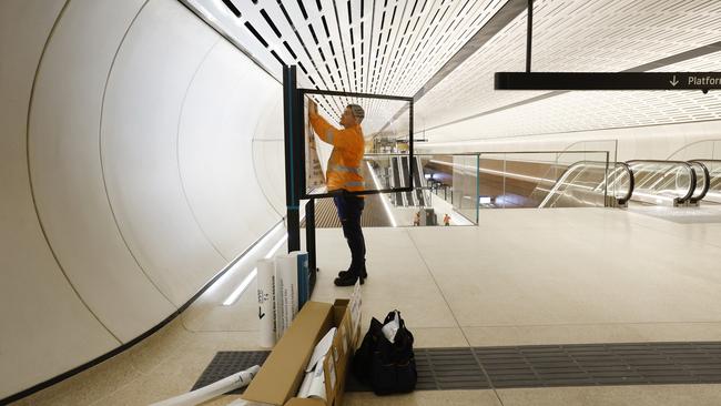 A worker putting up a station map at the entrance to the brand new Victoria Cross Metro Station in North Sydney. The Sydney Metro will be operational from the 12th of August. Picture: Richard Dobson