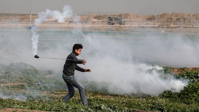 A Palestinian about to sling a teargas canister back to Israeli forces at the Gaza border with Israel. Picture: AFP