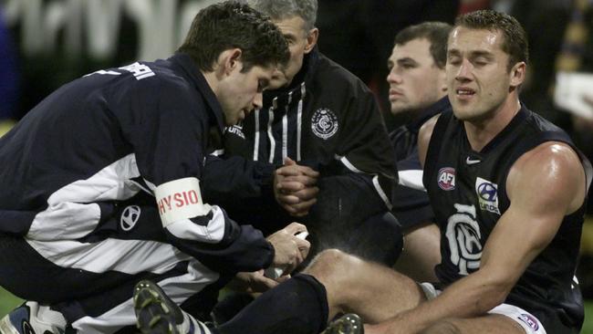 Carlton trainers try to help Anthony Koutoufides after his knee injury.