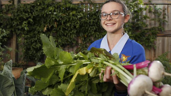 Redcliffe State School student Katie Brooks, 13, with produce grown at the Scarborough Masonic Centre community garden-a project run by Rotary and Freemasons. PHOTO: AAP/Regi Varghese