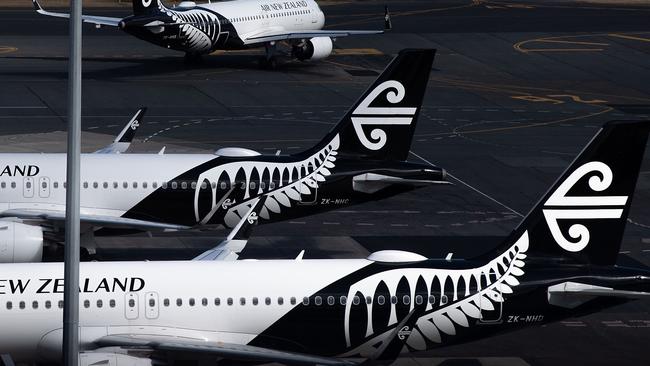 Air New Zealand airplanes wait for passengers outside the international terminal as a plane taxis at Wellington International airport on February 20, 2020. - The New Zealand government announced a bail out package to help the national carrier Air New Zealand survive the Corvid 19 virus down turn. (Photo by Marty MELVILLE / AFP)