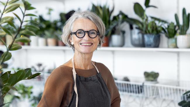 Portrait of senior female florist at small business flower shop. Happy mature woman wearing apron working in a small flower store; working in retirement happy retiree worker generic