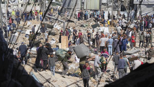 Palestinians collect belongings from a school used as a shelter by displaced residents that was hit twice by Israeli army strikes. Picture; AP.
