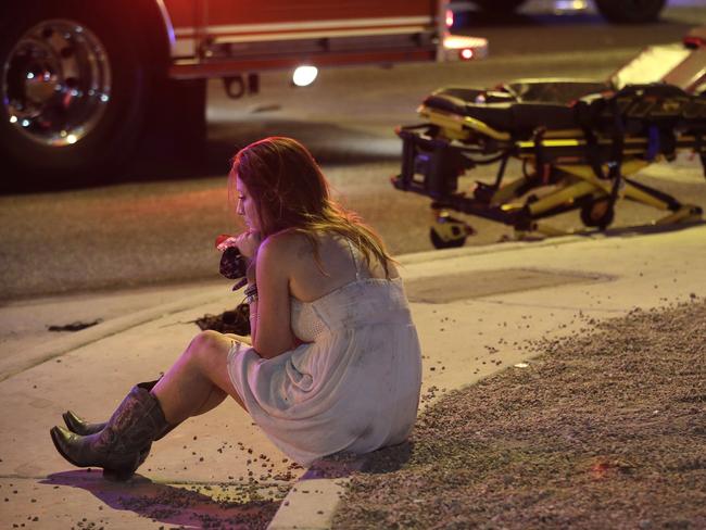 A woman sits on a curb at the scene of a shooting in Las Vegas. Picture: AP Photo/John Locher.