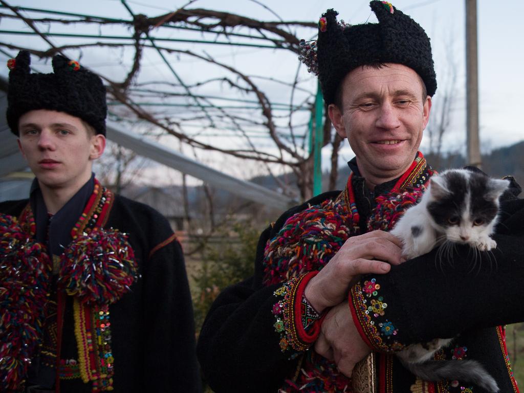 A man pets a cat while he and the rest of his group sing carols for a family as part of Orthodox Christmas celebrations in the Verkhovyna region. Picture: Getty