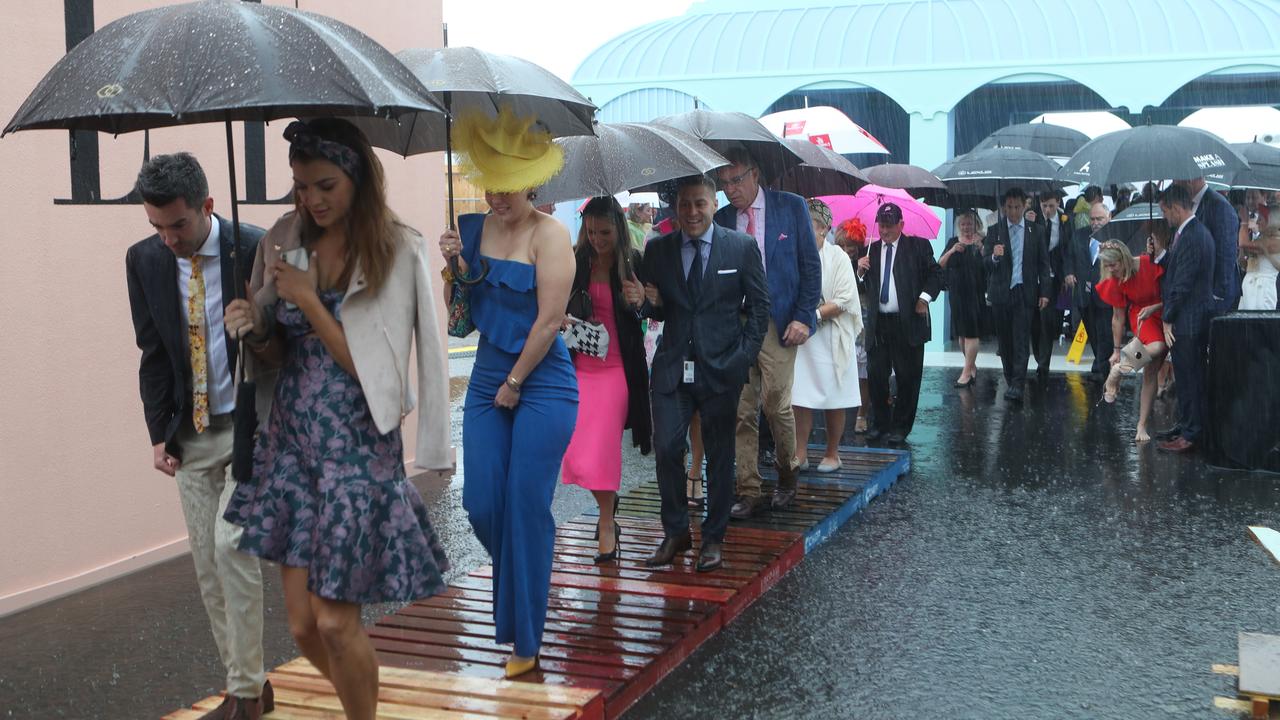 Racegoers make their way into the Birdcage through a flooded entrance. Picture: AAP Image/Dave Crosling