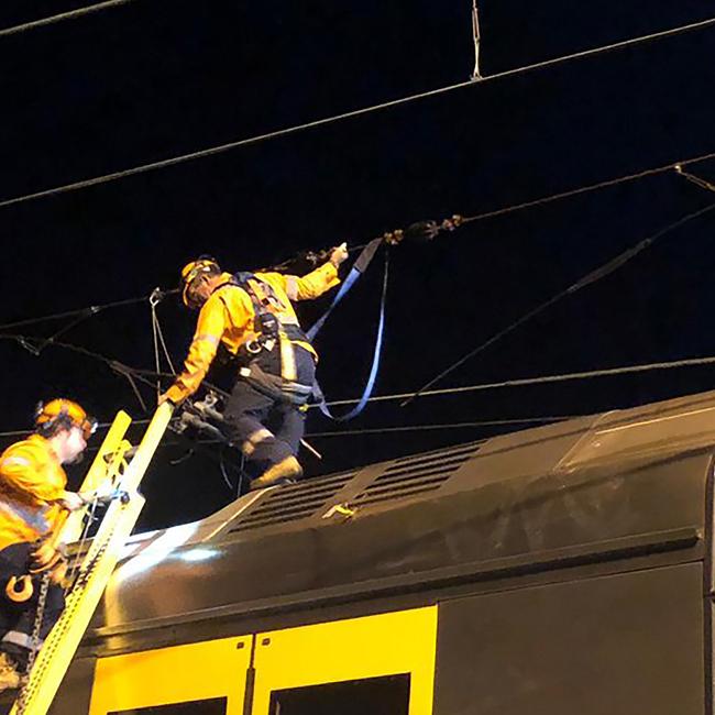 Engineers tend to overhead wiring over a train at Hornsby. Picture: Sydney Trains