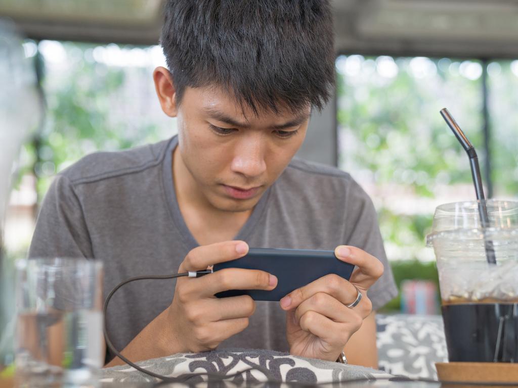 Young business Asian men using smart phone playing mobile game and relax with online shopping in his vocations