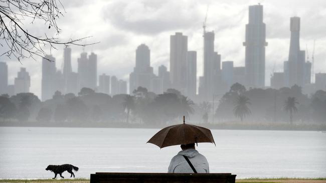 A man shelters under an umbrella at Albert Park Lake as a wintry storm passes over Melbourne. Picture: Andrew Henshaw