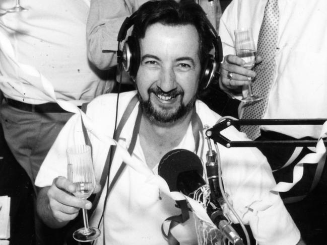 5AD radio announcer John Dean (front) sitting at desk in radio station, celebrating ratings win with colleagues (back l-r) Jeff Sunderland, Jeremy Cordeaux and Wayne Clouten, 26 Feb 1993.