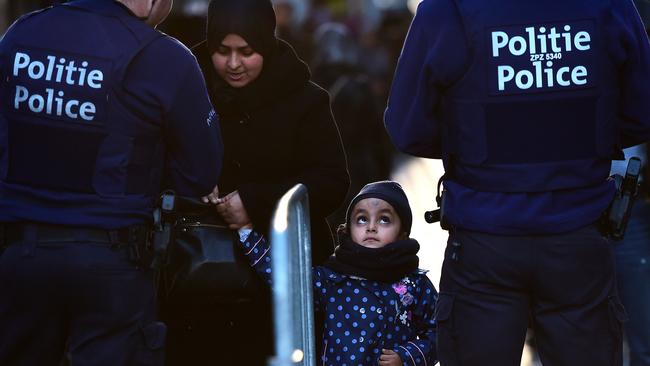 TOPSHOTS Police officers pat down a woman before entering the square where people take part in a candle light vigil to the victims of the Paris attacks in Brussels' Molenbeek district, on November 18, 2015. Molenbeek residents held a candle vigil at the town square where the Abdeslam family lives. AFP PHOTO / EMMANUEL DUNAND