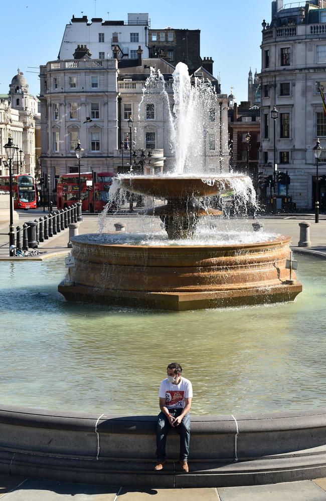 A lone mask-wearing man enjoys London’s springweather in an empty Trafalgar Square. Picture: AFP