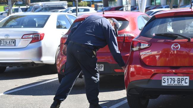 A parking Inspector marks a car at Glenelg. Council workers will be brought in to help police and health officials enforce quaratine rules for people who are meant to be isolating. Picture: AAP / Keryn Stevens