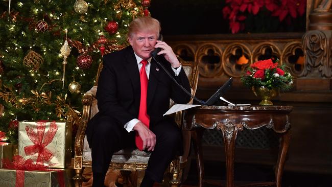 TOPSHOT - US President Donald J. Trump participates in NORAD Santa Tracker phone calls at the Mar-a-Lago resort in Palm Beach, Florida on December 24, 2017.  "NORAD Tracks Santa" is an annual Christmas-themed entertainment program, which has existed since 1955, produced under the auspices of the North American Aerospace Defense Command. / AFP PHOTO / Nicholas Kamm