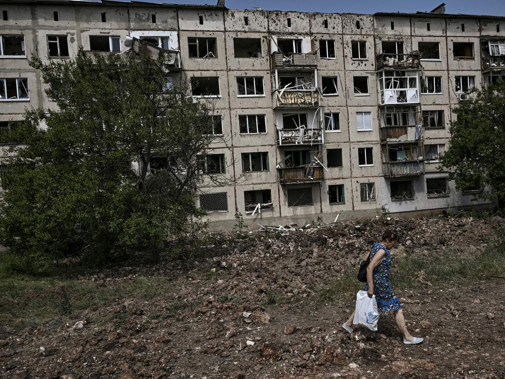 A woman walks in front of damaged apartment building after a missile strike in the city of Soledar, in the eastern Ukrainian region of Donbas.