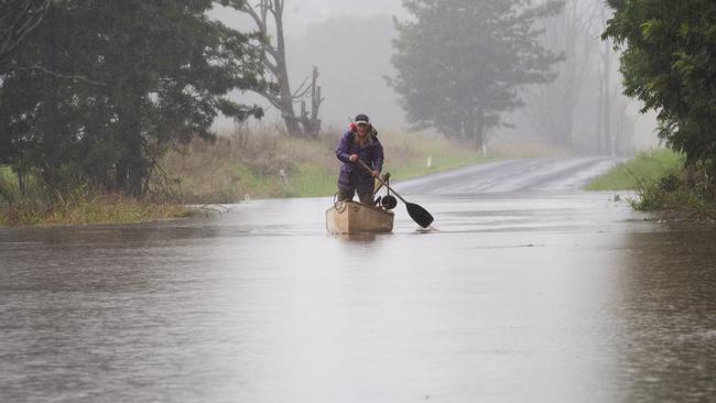 LISMORE, AUSTRALIA. NewsWire Photos. APRIL 5 2024. Rain has caused Eltham Rd in Eltham to close due to flooding on Friday April 5, 2024. Gwilym Summers paddles his canoe to get to the other side of the road.  Photo: NCA NewsWire/ Elise Derwin