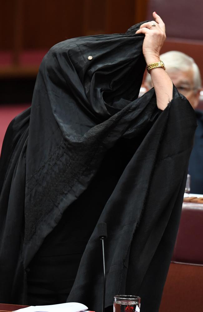 One Nation Senator Pauline Hanson begins taking off a burqa during Senate Question Time. Picture: AAP