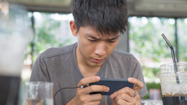 Young business Asian men using smart phone playing mobile game and relax with online shopping in his vocations